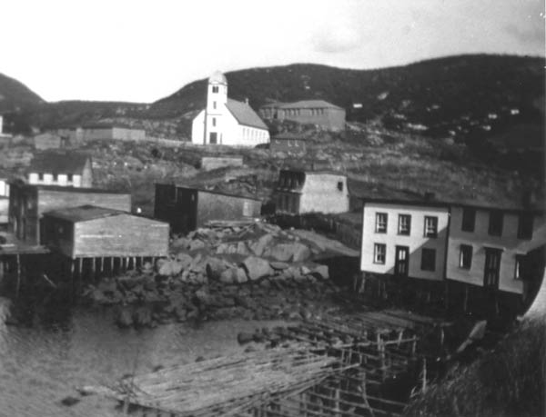 336: Red Island scene, church at center. Bill Rose's house back left, J V McCarthy's stage and lower  store at left; from right, Mike Reddy's house, his mother Mary Anne Reddy's house, and Will Rose's house (mansard roof)